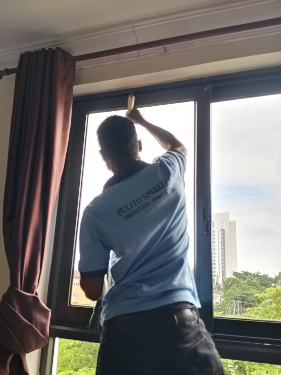 Pulito Sparkles team member cleaning a window